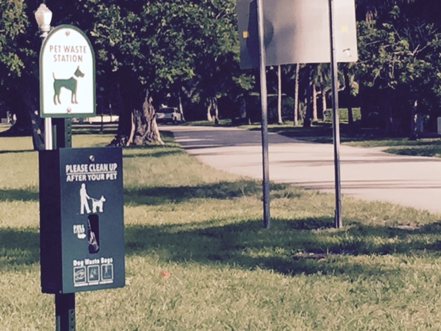 a sign posted, along with a plastic bag dispenser, for owners of dogs to pick up after their dogs
