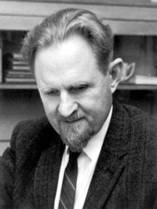 black and white photo of a man with a short beard wearing a jacket and a dark tie