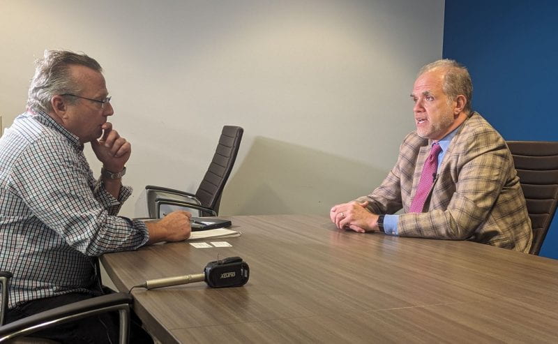 two men speaking with each other with a microphone on the table.