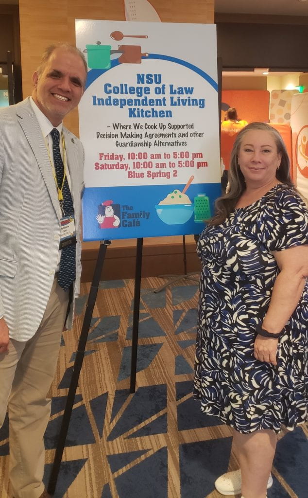 a man in a seersucker jacket and a woman in a blue dress next to a sign